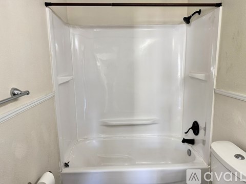 A white bathroom with a walk in shower and toilet paper on the roll.