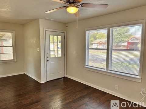 A room with a ceiling fan and two windows.