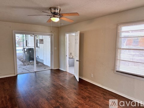 A room with a ceiling fan and sliding glass doors leading to a backyard.