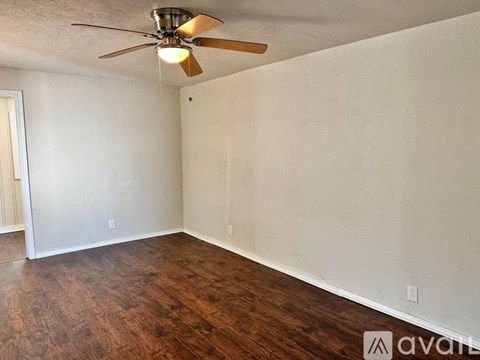 A room with a ceiling fan and wooden flooring.