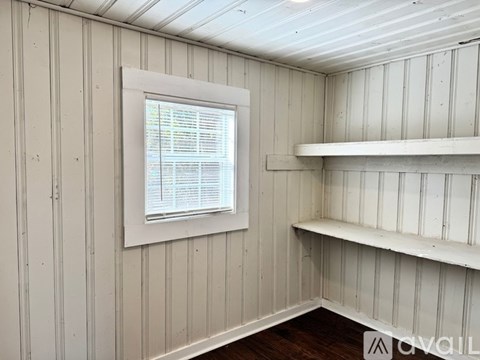 A white wall with a window and shelves.
