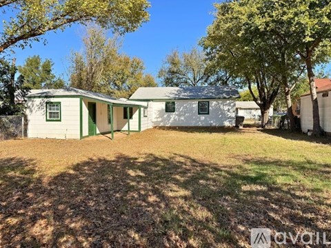 A white house with a green door and a tree in front.