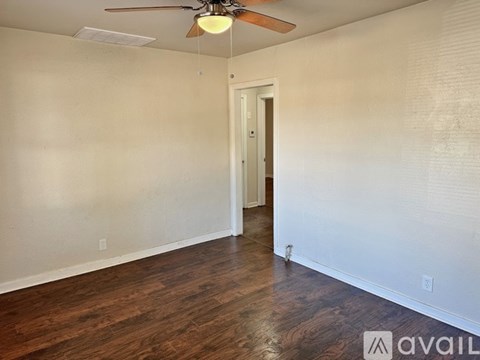 A room with a ceiling fan and wooden flooring.