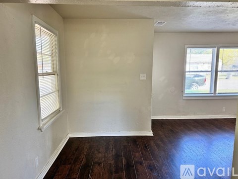 A room with wooden floors and a window with blinds.