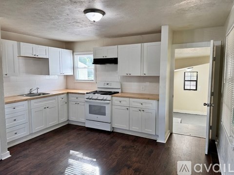 A kitchen with white cabinets and a wooden floor.