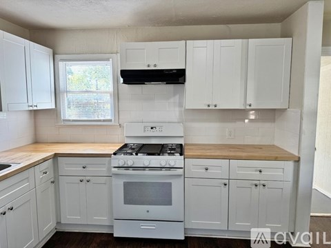 A kitchen with white cabinets and a stove top oven.