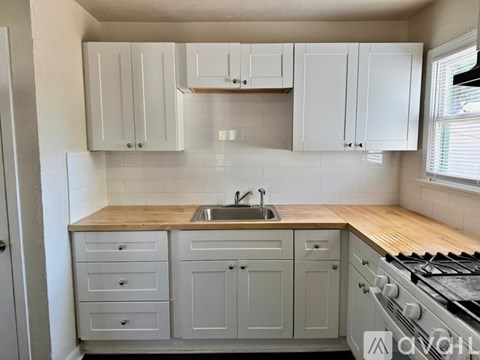 A kitchen with white cabinets and a wooden countertop.