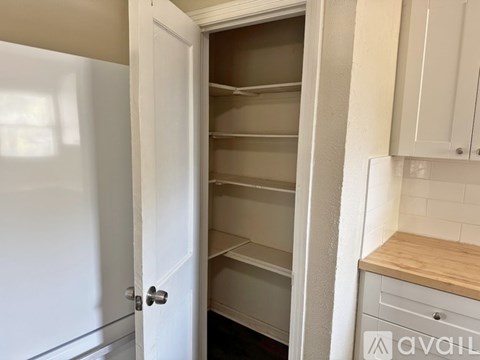 Empty white kitchen cabinets with a wooden countertop.