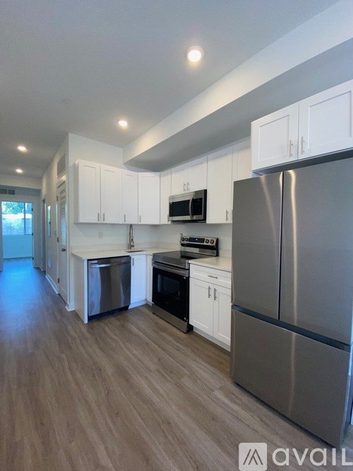 A modern kitchen with a refrigerator, microwave, and oven.