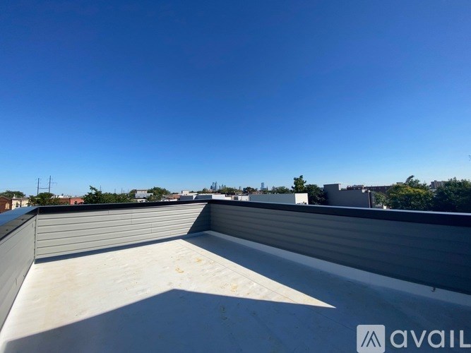 A rooftop with a clear blue sky and some buildings in the distance.