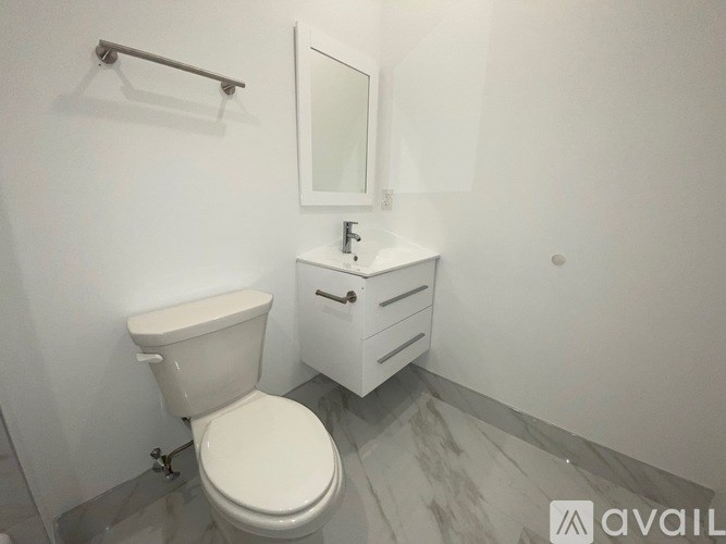 A white toilet sits in a bathroom with a white cabinet and mirror.