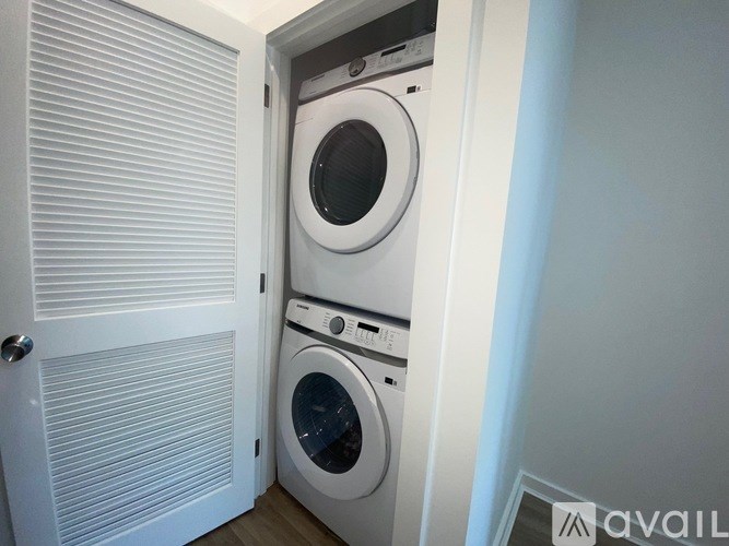A washing machine is in a small space between a door and a wall.