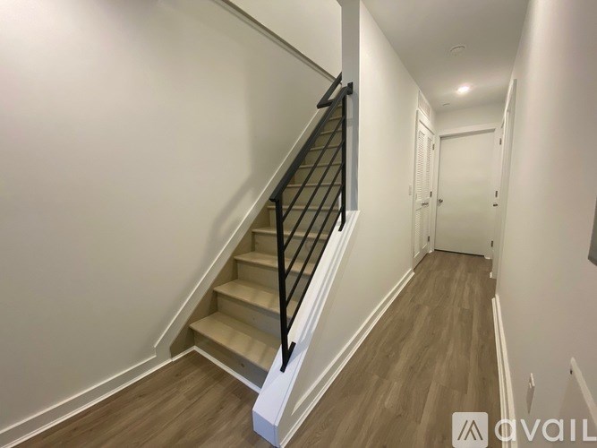 A hallway with a staircase and a door at the end.