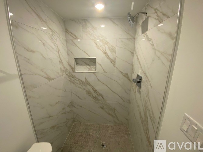 A bathroom with marble tiles on the walls and floor.