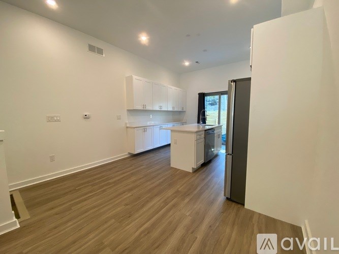 A spacious kitchen with white cabinets and a wooden floor.
