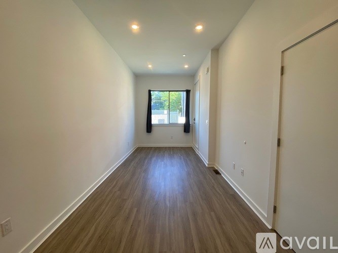 A long hallway with wood floors and white walls.