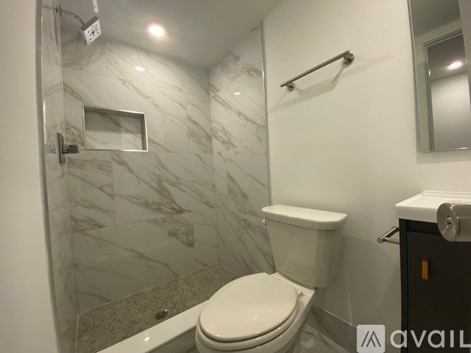 A bathroom with a toilet, a mirror, and a shower.