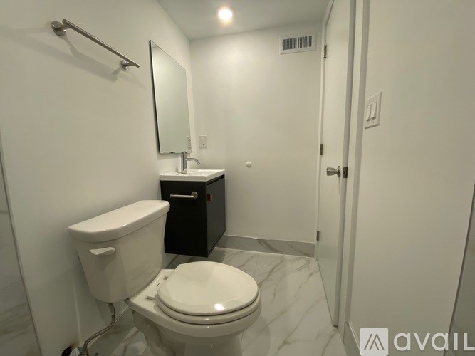 A bathroom with a toilet, sink, mirror, and a cabinet.
