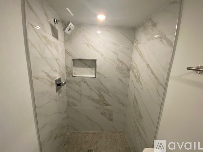 A bathroom with marble tiles and a shower.