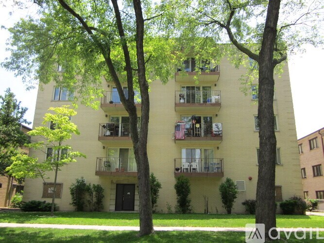 Apartment building with balconies and trees in front.