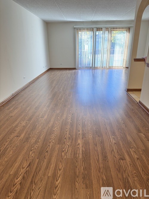 A room with wooden flooring and a window with blinds.