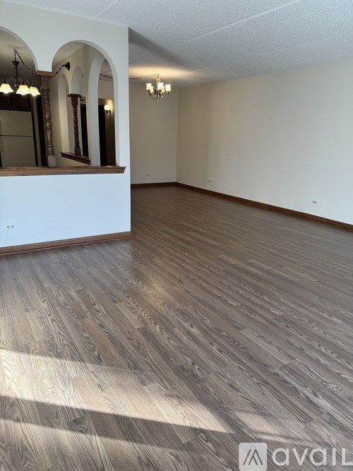 A room with wooden flooring and a white wall with a mirror and lights.