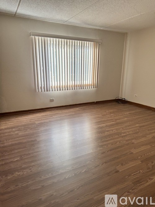 A room with wooden flooring and a window with blinds.