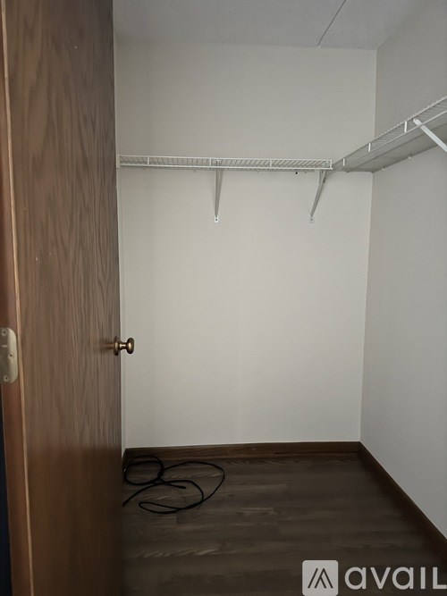 A room with a wooden door and a white wall with a shelf above it.