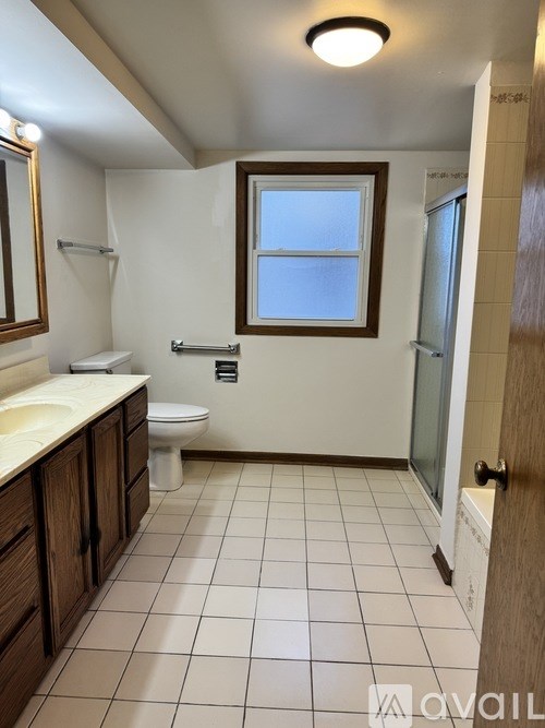 A bathroom with a toilet, sink, and a window.