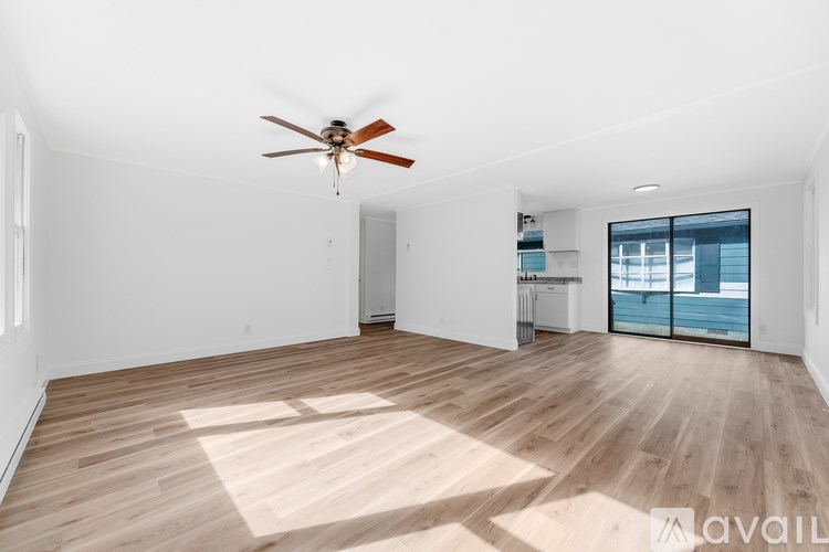 A spacious room with a ceiling fan and wooden flooring.