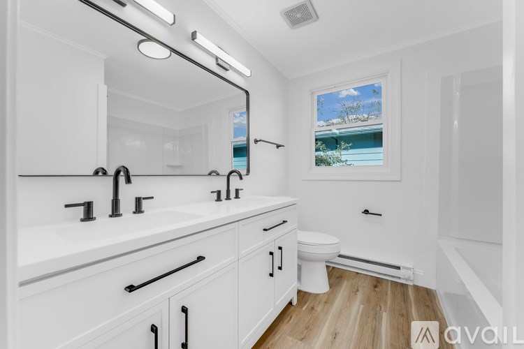 A white bathroom with a large mirror and a window showing a blue house.