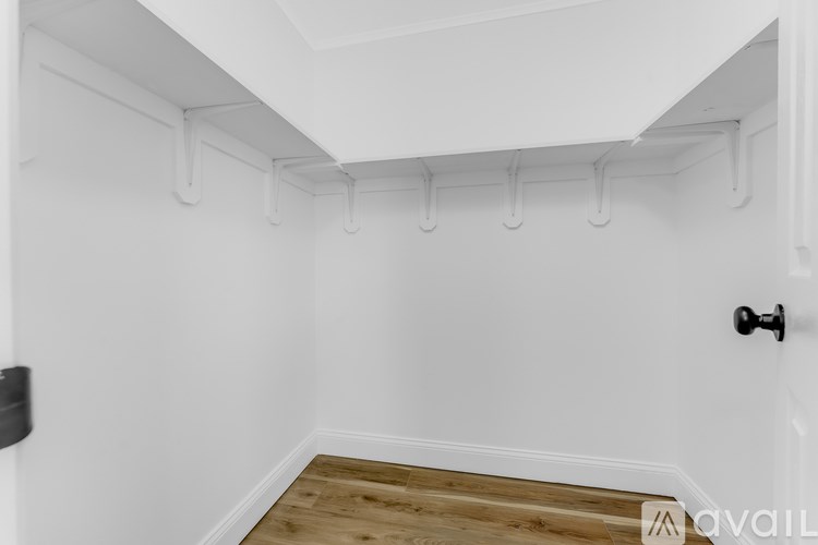 A white room with a door and a wall of pipes.