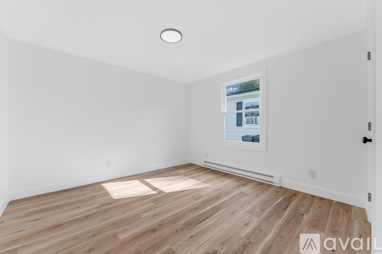 A room with wooden flooring and a window showing a view of a building.