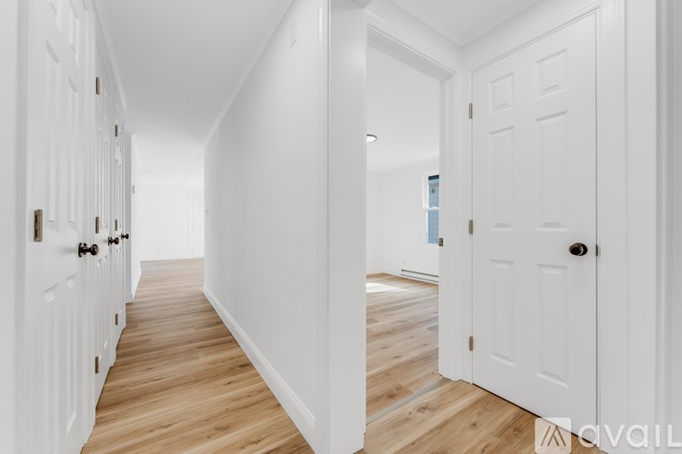A hallway with white doors and wooden floors.