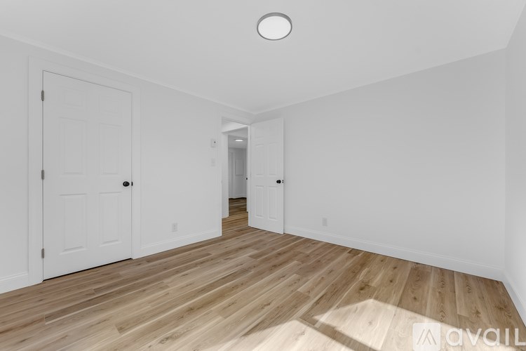 A spacious room with wooden flooring and white walls.