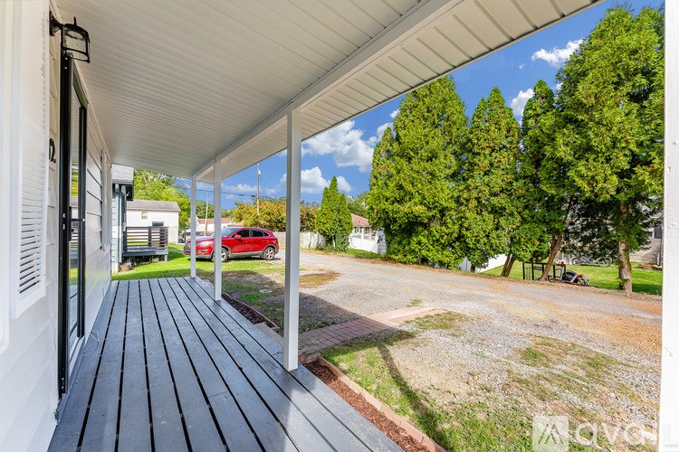 A red car is parked in the driveway of a house.
