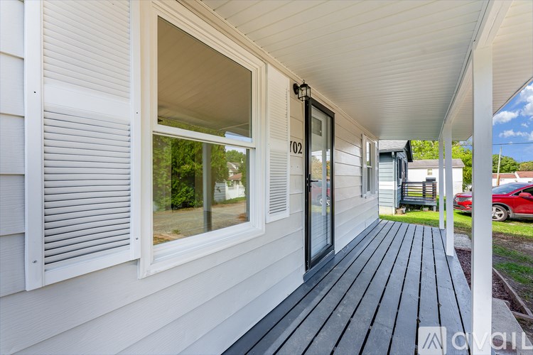 A white house with a black deck and a window with blinds.