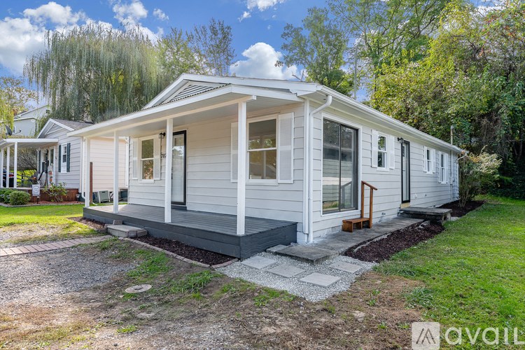 A white house with a porch and a small garden in front.