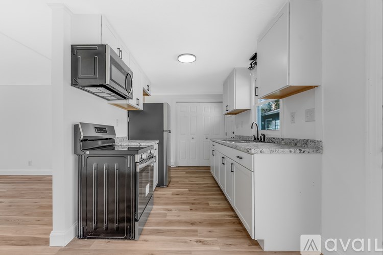 A kitchen with white cabinets and a black fridge.