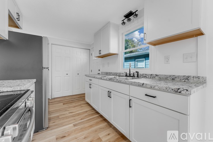 A kitchen with white cabinets and a marble countertop.