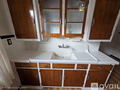 A white sink is in a wooden cabinet.