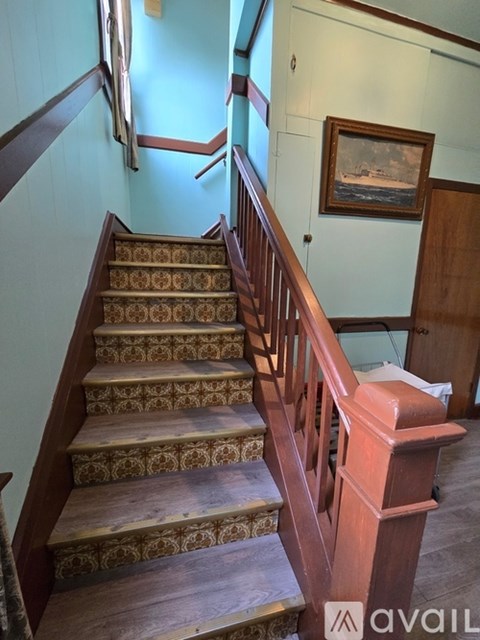 A staircase with a wooden handrail and a painting hanging on the wall.