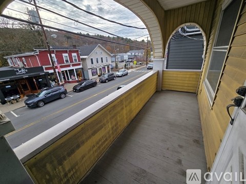 A view from a balcony overlooking a street with cars and buildings.