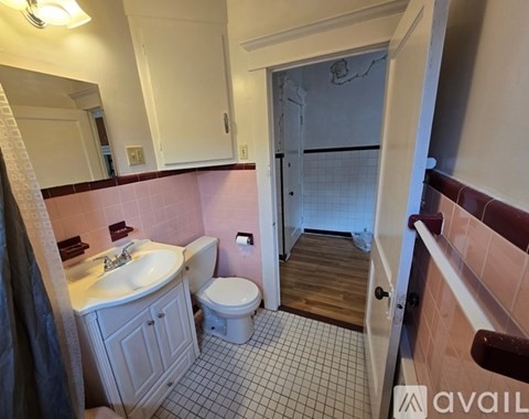 A bathroom with a sink, toilet and a wooden floor.