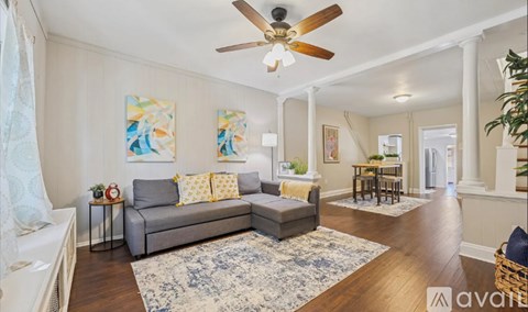 A living room with a grey couch and a ceiling fan.