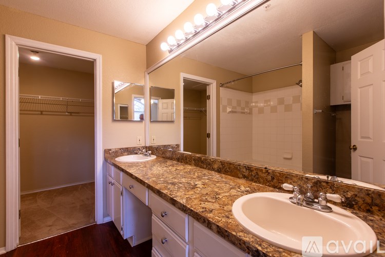 A bathroom with a granite countertop and a vanity with a sink and mirror.