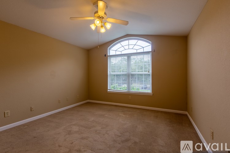 A room with a ceiling fan and a window with blinds.