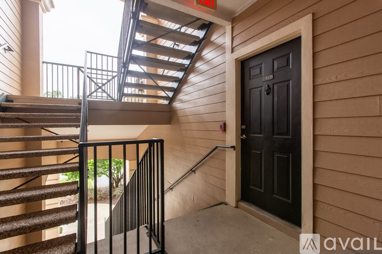 A wooden staircase with a metal railing leads to a door.
