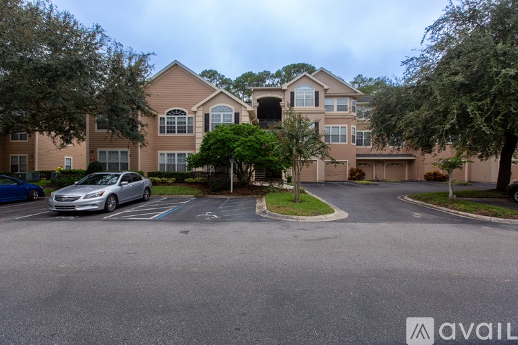 A silver car is parked in a parking lot in front of a building.