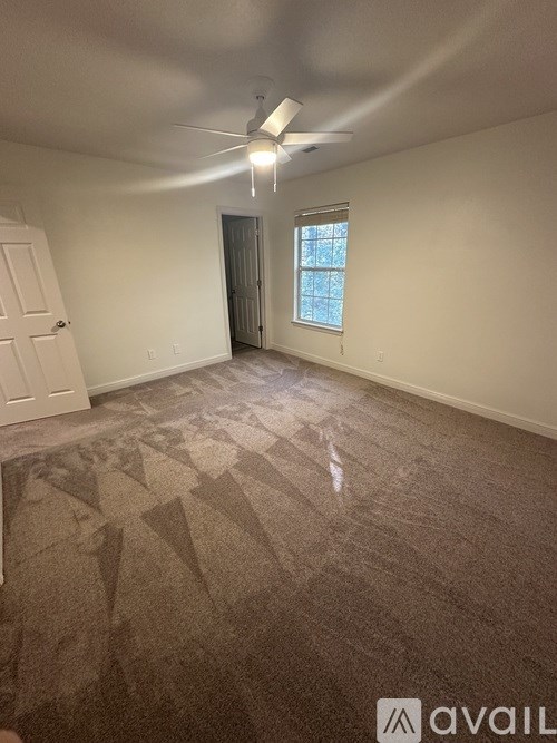 A room with a carpeted floor and a ceiling fan.